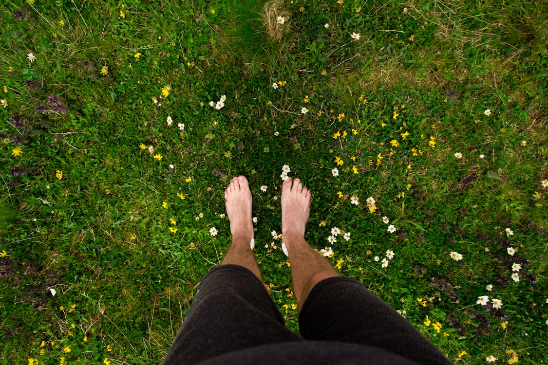 Pieds nus dans l'herbe, symbolisant le retour aux soins naturels.